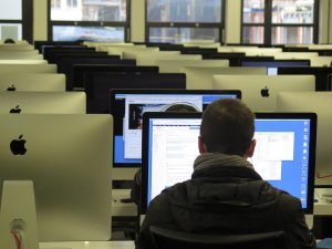 man sitting in front of a computer in a room filled with computers.