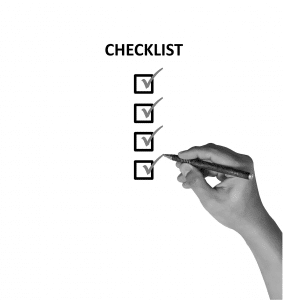 hand with pen checking off a checklist.