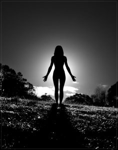 silhouette of a woman standing in mountain pose.