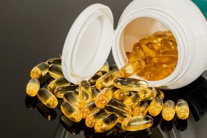 pill container opened laying down with yellow pills coming out of it on the table.