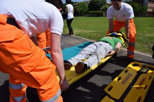 man on a stretcher being picked up by two men in orange pants.