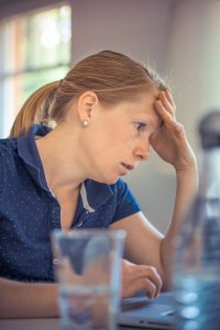 caucasian woman with palm on her forehead looking at something