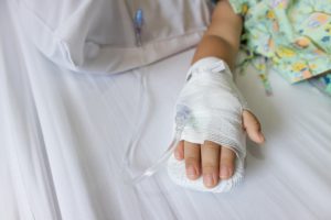 hand of a little kid with bandage over it and an IV connected in it. 
