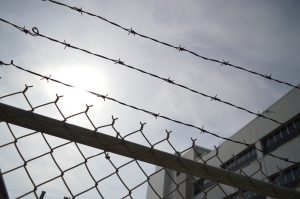 barbed wire over a fence and building in the background