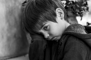 black and white picture of a little boy that is sad