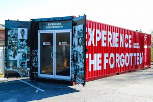 red shipping container with doors open and "experience the forgotten" on the side