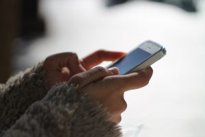 caucasian womans hands holding a white cell phone.