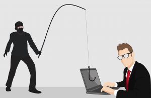 cartoon os a person in all black with phishing pole tryingo to hook onto a businessman in front of a laptop