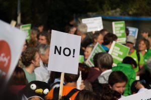 people in a crowd with signs with one in particular that says "no!"