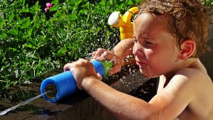 young little caucasian kid with a water gun squirting it.