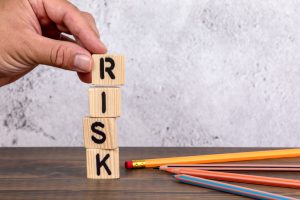 risk spelled out on wooden blocks with a hand on the R
