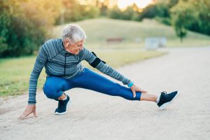 older woman in workout attire stretching