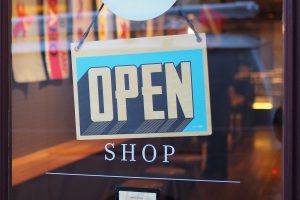 blue and white sign that says open with shop underneath it