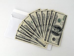 hundred dollar bills spread out over a white envelope.