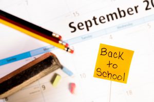 back to school post it note with school materials around.