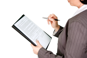 woman in a business uit with a form in her hand and pen in the other. 
