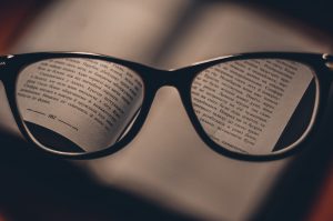 glasses with words on each lens from a book in the background