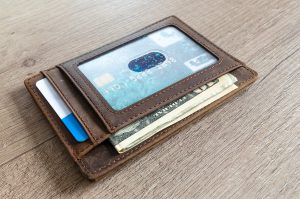 brown leather wallet with clear screen showing card and money in it