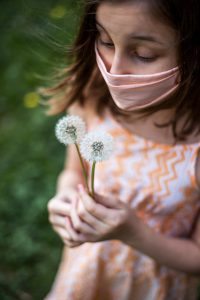 little girl wearing a mask holding flowers