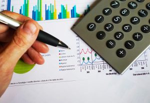different analytics with calculator and graphs and a hand holding a pen.