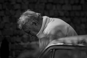 black and white picture of older man sitting down and looking down.