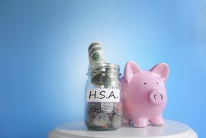 pink piggy bank next to a jar that has money in it labeled HSA