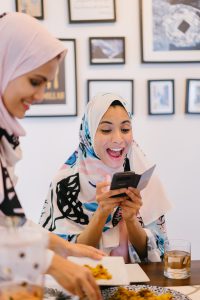 woman with hijab on looking at her phone smiling