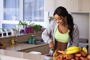 african american woman in sports bra cutting fruit