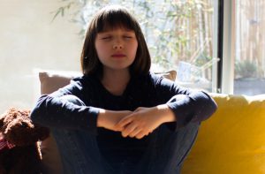 caucasian girl sitting on a couch with her eyes closed