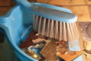 blue dustpan and brush with glass in the dustpan