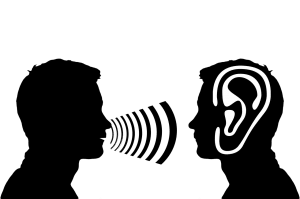 silhouette of 2 people with one speaking into the others ear