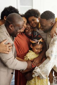 african american family in a huddle hugging.
