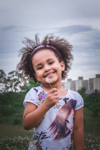 young girl smiling holding a dandelion