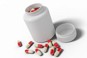 plain white bottle with red and white pills in it and some on the table next to the bottle.