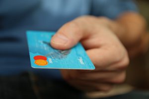 caucasian hand holding a blue debit card. 