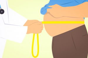 doctors hands wrapping a measuring tape around a mans belly.