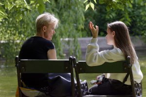 caucasian mom and daughter sitting outside on a bench talking