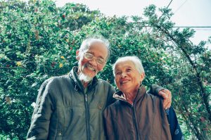 older asian man and woman smiling with the mans arm around the woman's shoulder