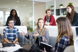 group of people in the workplace gathered around each other talking