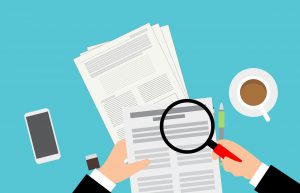 hand holding a magnifying glass over paperwork