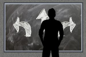 silhouette of a person standing in front of 3 arrows pointing in 3 different directions