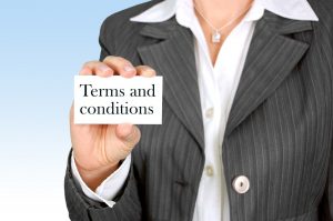 woman s torso in a suit holding a paper with "terms and conditions" on it