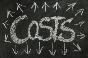 costs with arrows pointing outwards all around word written on a blackboard.