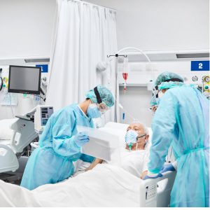 doctors dressed head to toe with protective gear seeing an elderly man with a mask on.