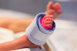 premature baby's little foot with cuff around it with red light inside.