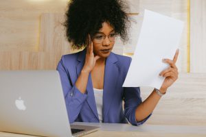 african american in a blue suit woman confused holding a piece f paper