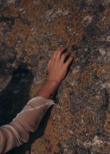 caucasian hand touching a wall with mold all over it