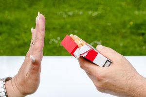 caucasian hand turning down a cigarette from a box being held by someone else