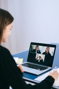 caucasian woman in front of a laptop with people on the screen