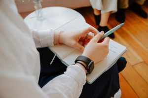caucasian hands on a notebook while holding a pen